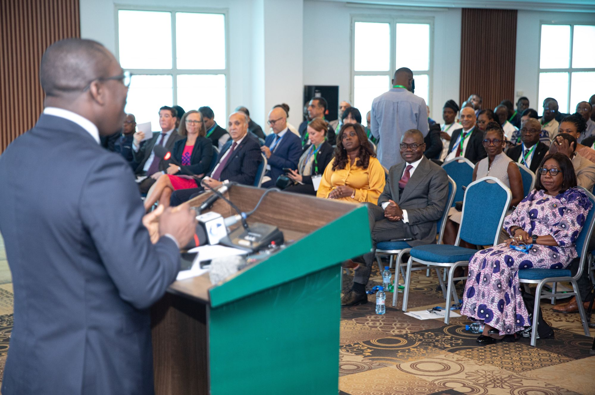 Speaker at a podium facing a packed conference hall